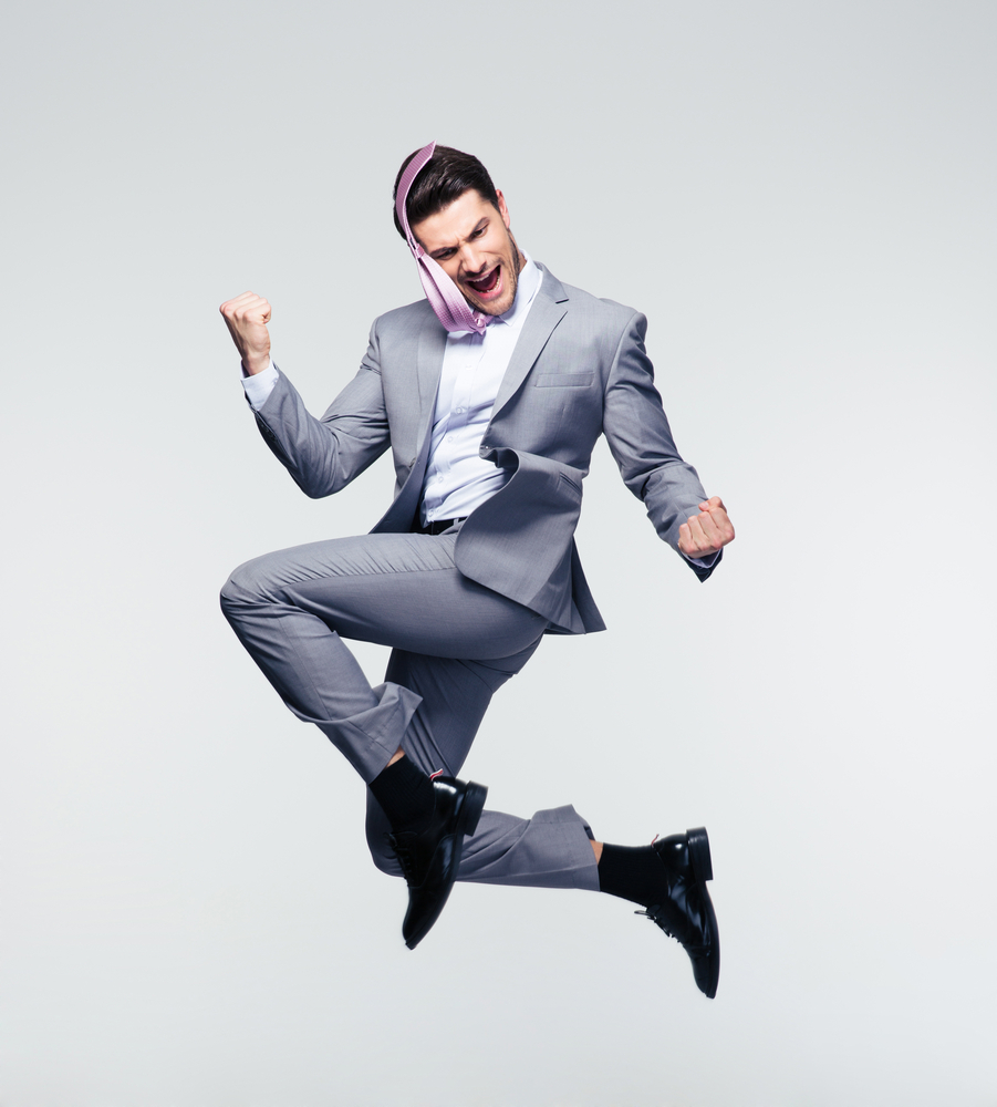 Happy businessman jumping in air over gray background